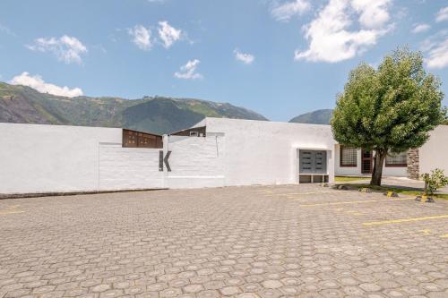 a white building with a tree in a parking lot at Taz's house in Hacienda Yacucalle