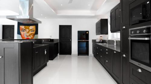 a large kitchen with black cabinets and white tile floors at Villa sun in Amphoe Koh Samui