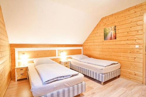 two beds in a room with wooden walls at Modernes Ferienhaus mit Kamin & Garten in ruhiger Lage in Hasselfelde