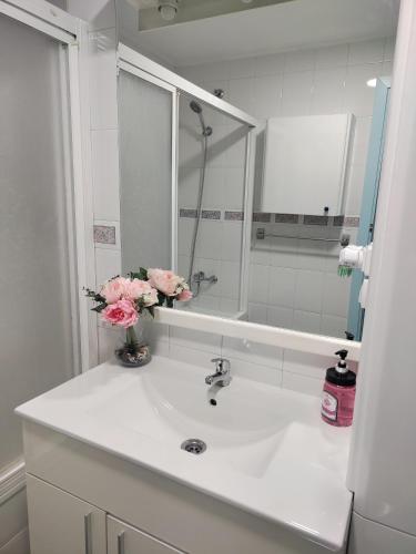a bathroom with a sink with a mirror and flowers at Hikari&Sineida Home in Rincón de la Victoria