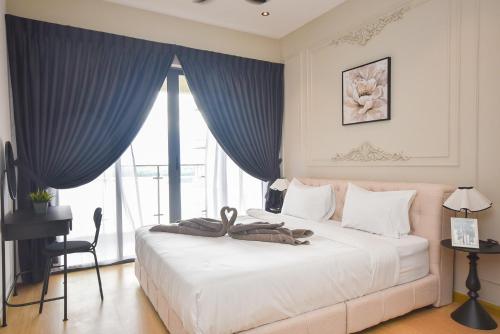 a bedroom with a large white bed with blue curtains at Country Garden Seaview Suite by Nest Home at Danga Bay in Johor Bahru