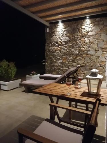 a patio with a wooden table and a stone wall at Remezzo in Koutalás