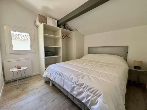 une chambre avec un lit blanc et une fenêtre dans l'établissement Maison 3 pièces 4 couchages Saint Georges d'Oléron SGO000-098, à Les Sables Vignier