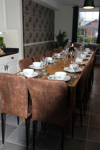 a long table with chairs and wine glasses on it at Beautiful 7 Bedroom House With Hot Tub Sleeps 14 in Great Ouseburn