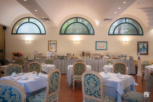 a dining room with tables and chairs with white tablecloths at Aldrovandi Residence City Suites in Rome