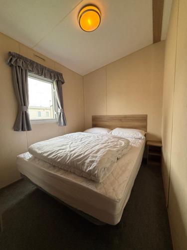 a bedroom with a white bed with a window at Jay 28, California Cliffs, Parkdean, Sleeps Eight, Free Wi-Fi, Pet Friendly, Bed Linen and Towels Included in Great Yarmouth