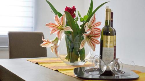 a bottle of wine and a vase of flowers on a table at Apartments Pravica Trebinje in Trebinje