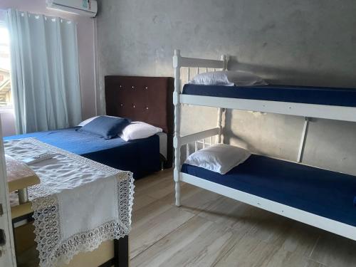 a room with two bunk beds and a table at Hospedagem Doce lar in Joinville