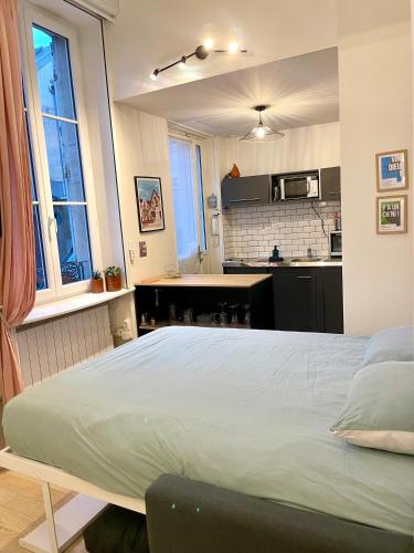 une chambre avec un grand lit et une cuisine dans l'établissement Studio Cosy Le Bareuzai, à Dijon