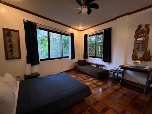 a living room with a bed and a couch and windows at Argonauta Boracay Apartment Suites and Villas in Boracay