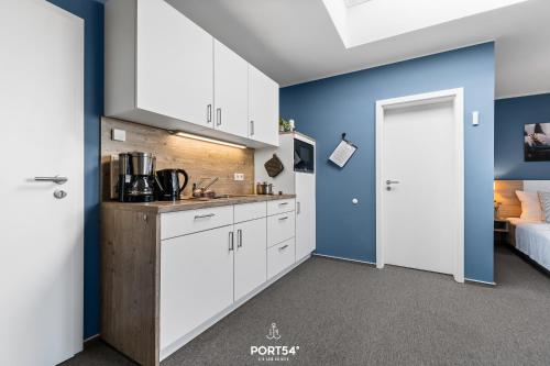 a kitchen with white cabinets and a blue wall at Ferienwohnung Bude 5 Dagebüll in Dagebüll