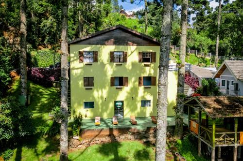 an aerial view of a yellow house with trees at Pousada Casa de Campos Guest House by Concavus in Campos do Jordão