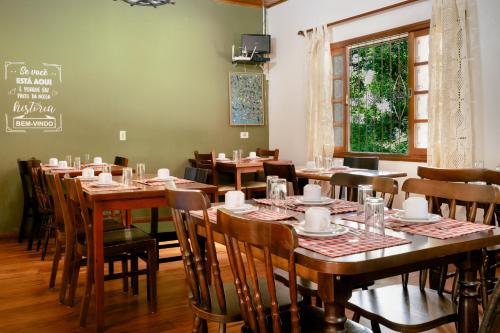 a dining room with tables and chairs and a chalkboard at VELINN Pousada Casa de Campos Guest House in Campos do Jordão