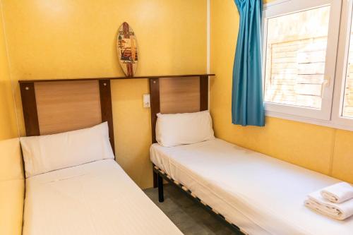 two beds in a small room with a window at HolaCamp Sant Salvador in Comarruga