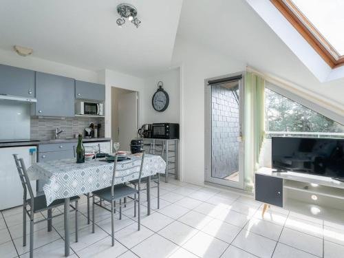 une cuisine avec une table et des chaises et une cuisine avec une horloge dans l'établissement Studio Confortable à 500m des Plages de Carnac - Balcon Sud, TV, Parking - 2 Pers, 2* - FR-1-477-181, à Carnac
