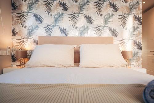 a bed with two pillows in a bedroom with a wallpaper at 2BR LXRY Jansofat tropic oasis apt & pool in Willemstad