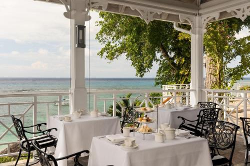a dining room with white tables and chairs and the ocean at Sandals Royal Plantation All Inclusive - Couples Only in Ocho Rios