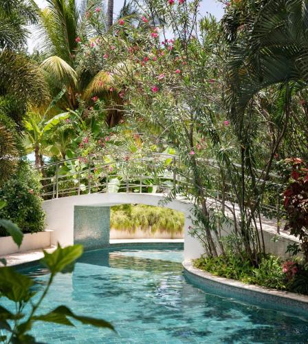 a bridge over a swimming pool in a garden at Sandals Halcyon Beach All Inclusive - Couples Only in Vigie
