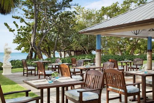 an outdoor patio with tables and chairs and the ocean at Sandals South Coast All Inclusive - Couples Only in Savanna-la-Mar