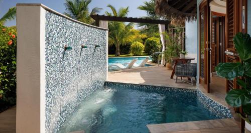 a swimming pool with a tile wall next to a house at Sandals South Coast All Inclusive - Couples Only in Savanna-la-Mar