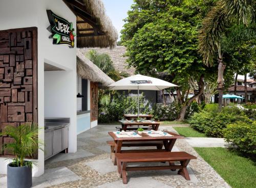 a patio with two picnic tables and an umbrella at Sandals Royal Barbados All Inclusive - Couples Only in Christ Church