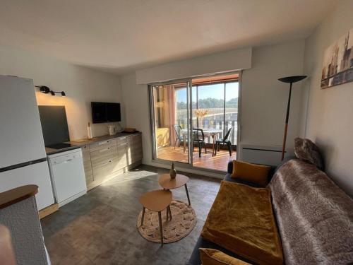 Il comprend un salon avec un canapé et une cuisine avec un balcon. dans l'établissement Appartement proche plage avec piscine, parking et animaux admis - FR-1-413-215, à Capbreton