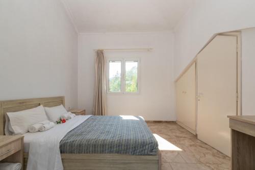a white bedroom with a bed and a window at Markella Maisonette Hotel Complex in Marathias