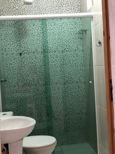 a bathroom with a shower with a toilet and a sink at Pousada Simples José in Cachoeira Paulista