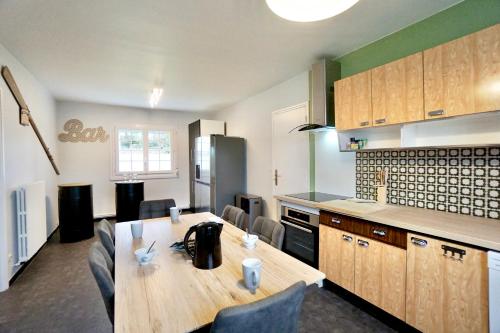 une cuisine avec une table en bois avec des chaises et un comptoir dans l'établissement Ti Maen - 150m de la mer, à Ploemeur