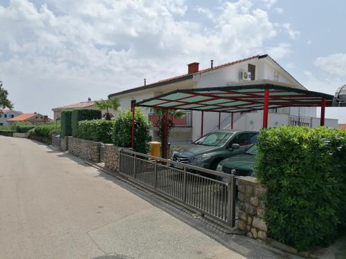 a car parked under a covering in front of a house at APARTMAN GLORIA in Krk