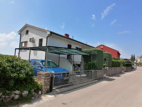 a house with a blue car and an umbrella at APARTMAN GLORIA in Krk