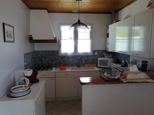 une cuisine avec des armoires blanches et une fenêtre dans l'établissement Maison Ile de Ré, à Sainte-Marie de Ré