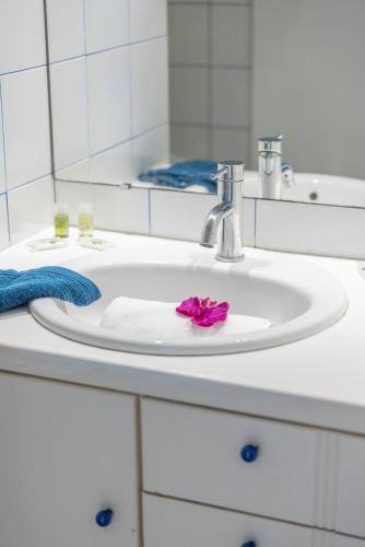 - un lavabo avec une fleur rose sur une serviette dans l'établissement NEW SANTORINI - INCROYABLE VUE SUR MER - WIFI - GARAGE TopProsConciergerie, à La Grande Motte