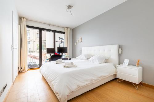 une chambre blanche avec un grand lit blanc et une fenêtre dans l'établissement Appartement - Paris, France, à Paris
