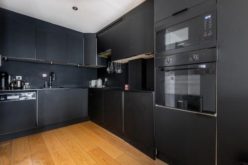 une cuisine noire avec des armoires et des appareils noirs dans l'établissement Appartement - Paris, France, à Paris