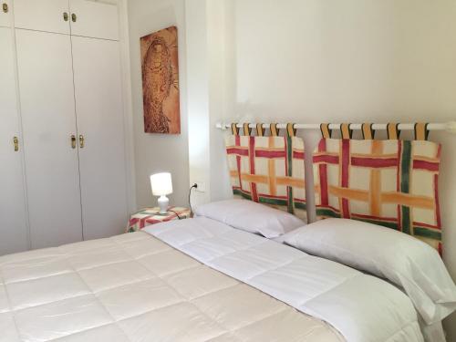 a bedroom with a white bed and a white cabinet at Apartamento Rosendo in Calafell