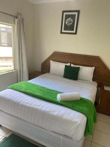 a bedroom with a bed with a green blanket on it at Wellcome Dover Lodge in Lusaka