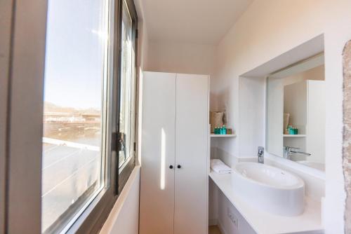 a white bathroom with a sink and a window at Bravissimo Calderers La Lleona, heart of the Barri Vell in Girona