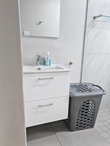 a white bathroom with a sink and a trash can at 37 Chakas Rock Chalets in Ballito