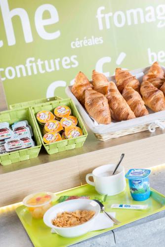 a table with a tray of pastries and a plate of food at Ibis Budget Béziers Est La Giniesse in Béziers