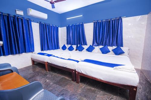 2 letti in una camera con tende blu di Doubleonestays Hotel a Pondicherry