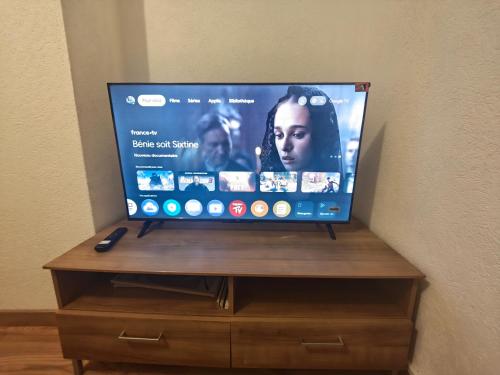 a flat screen tv sitting on top of a wooden stand at Chambre climatisée et cosy Auberge du manala Hôtel 24 24 in Saint-Louis