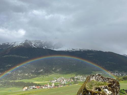a rainbow over a town in a valley with mountains at Ferienwohnung Visoura in Reams