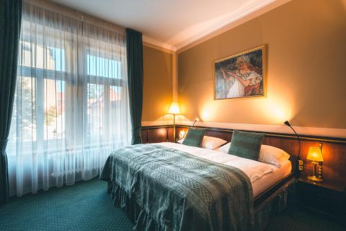 a bedroom with a bed and a large window at Hotel Hastal Prague Old Town in Prague