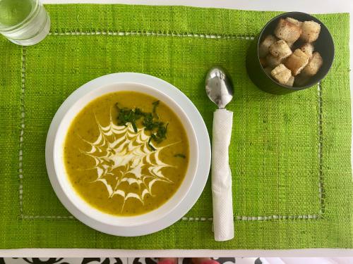 a bowl of soup on a table with a spoon at Hôtel ESCALE - Aéroport Ivato in Ivato