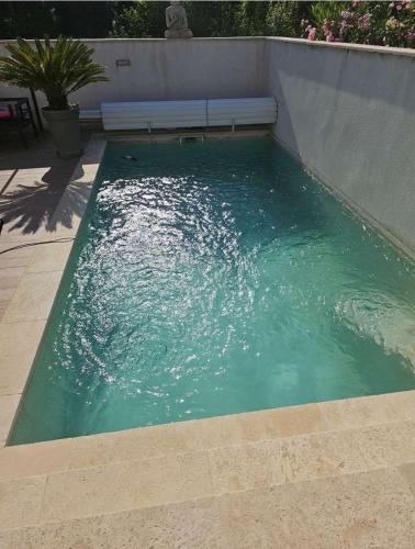 un bassin d'eau verte avec un banc dans l'établissement Charmante maison avec piscine, à Solliès-Toucas