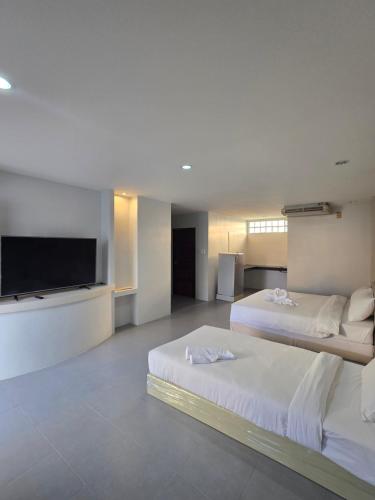 a hotel room with two beds and a flat screen tv at Middle tree house pattaya in Pattaya