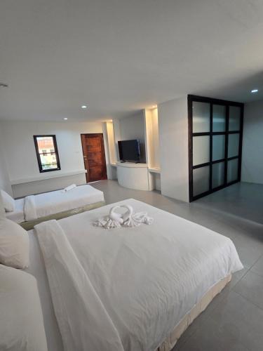 a large bedroom with two beds with white sheets at Middle tree house pattaya in Pattaya