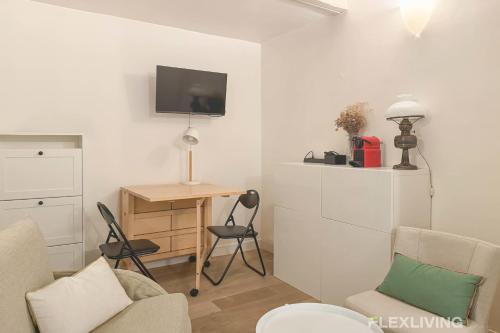 Elle comprend un salon avec un bureau et une télévision murale. dans l'établissement Flexliving - Studio - Duvivier, à Paris
