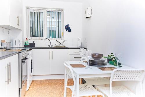 Una cocina blanca con una mesa y sillas blancas. en Emerald Excel City Airport o2 Apartment, en Londres